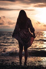 Poster - Silhouette of a female standing on a beach at the golden hour