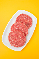 Wall Mural - Three raw red meat burgers for hamburgers of minced ground beef on dish