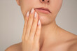 a young Caucasian woman is experiencing severe toothache holding her lower jaw with her hand, close-up. Timely dental treatment.