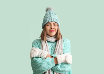 Frozen young woman in winter clothes on green background