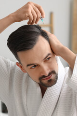 Wall Mural - Handsome man with injection for hair growth in bathroom, closeup