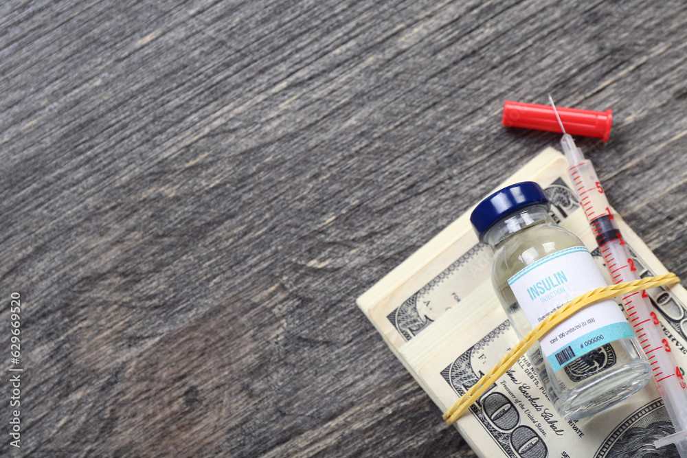 Insulin with syringe and money on dark wooden background. Expensive medicine concept