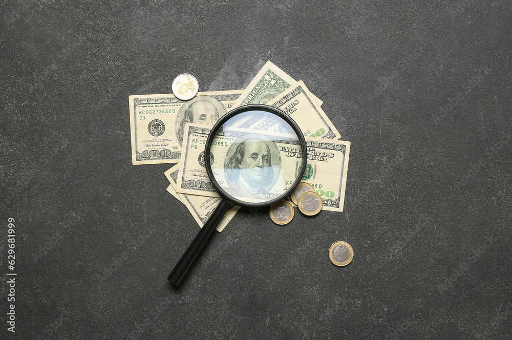 Magnifier with one hundred dollars on grunge black background