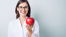A Beautiful Woman In The Nutritionist Outfit With An Apple In Her Hand On A White Background