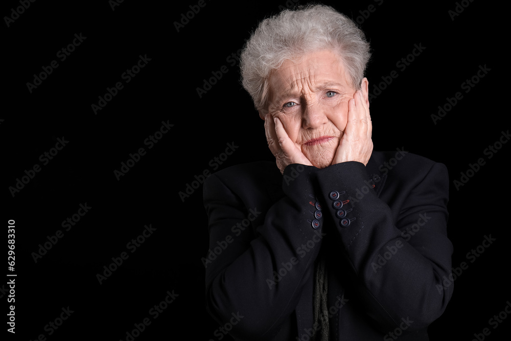 Sad senior woman on black background, closeup
