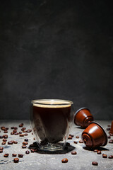 Wall Mural - Glass of delicious coffee, capsules and beans on grey grunge table