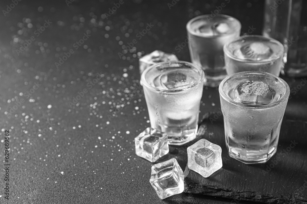 Shots of vodka with ice cubes on black background
