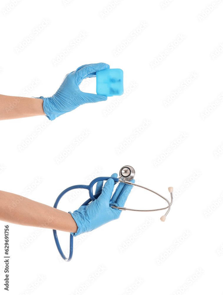 Female doctor's hands holding stethoscope and pill box on white background