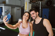 © JoseIMartin - brunette fitness couple taking a selfie with their cell phone smiling after finishing their workout