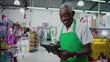 © Marco - One Black Brazilian Senior Employee of Supermarket with Tablet, Inside Grocery Store. Portrait close-up face of an African American person at workplace