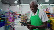 © Marco - One Black Brazilian Senior Employee of Supermarket with Tablet, Inside Grocery Store. Portrait close-up face of an African American person at workplace