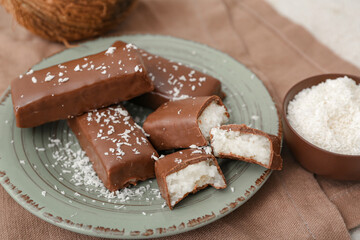 Wall Mural - Plate with tasty chocolate covered coconut candies on table