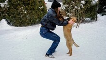 Happy Teenage Girl Playing With Her Puppy In Snow At House Backyard. Kids With Animals, Games With Pets.