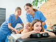 © JackF - Satisfied girl relaxing in spa center while two professional massagists performing back maderotherapy massage with wooden rolling pin