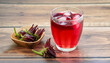 Fresh Roselle flower ( Jamaica sorrel, Rozelle or hibiscus sabdariffa ) and glass of sorrel juice ice tea isolated on wooden table background.