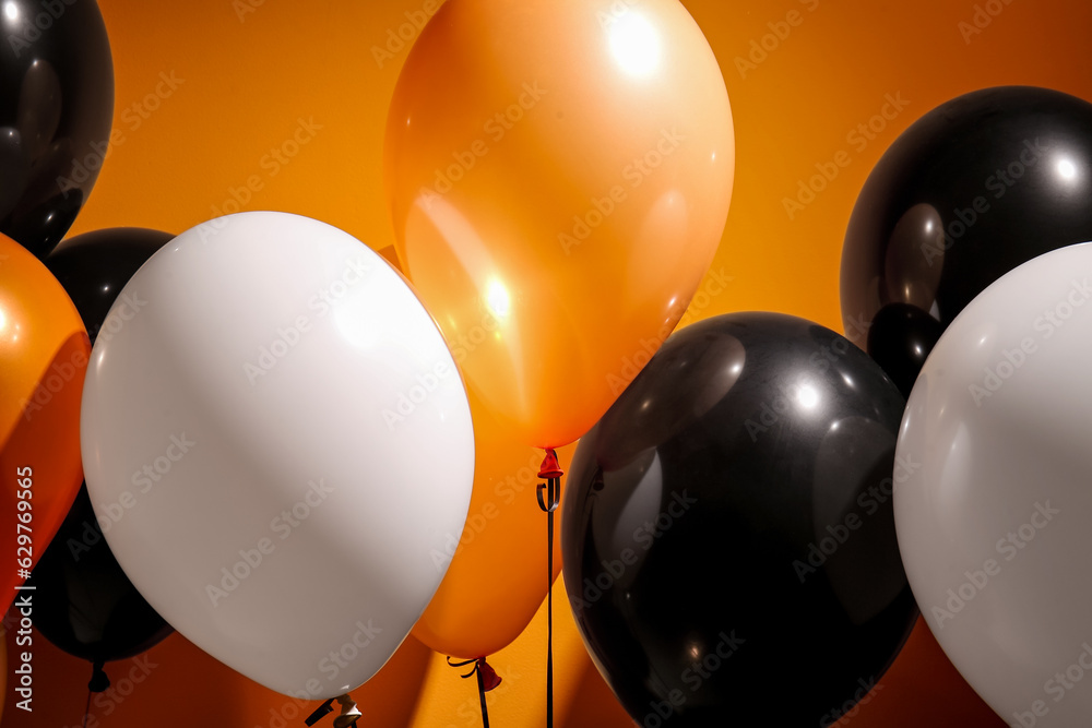 Different Halloween balloons on orange background, closeup