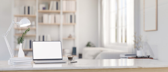 A laptop mockup on a tabletop with a blurred modern white living room as a background.