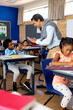 © WavebreakMediaMicro - Diverse male teacher teaching school boy using sign language in class at elementary school