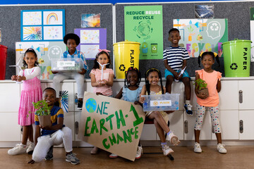 Wall Mural - Portrait of happy diverse children with ecology items and plants in class at elementary school