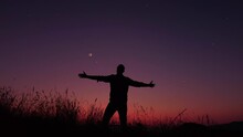 Man With Arms Wide Open Enjoying Outdoors Under Stars, Planets And Moon.
