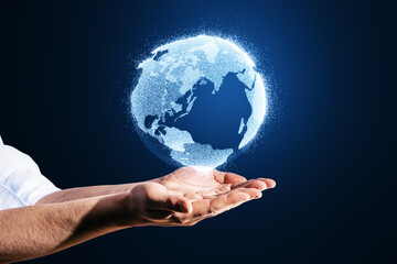 Wall Mural - Close up of man hands holding glowing globe hologram on blurry blue background. Digital earth and metaverse concept.