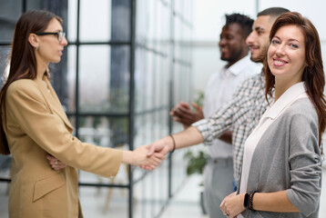 ambitious business woman smiling at the camera against the backdrop of a meeting of colleagues