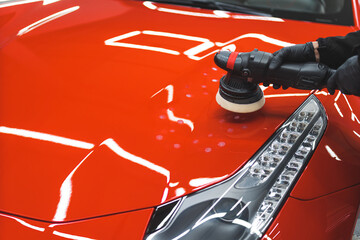 Wall Mural - closeup shot of a car specialist with black gloves holding an orbital polisher and cleaning a car. High quality photo