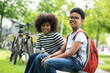 © zinkevych - Two friends young girl boy sitting on bench in park enjoying summer green outdoors.