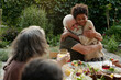© pressmaster - Affectionate senior man embracing his African American grandson while sitting by dinner table served with healthy and tasty homemade food