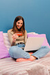 © Jose Calsina - Vertical portrait of young woman using a credit card and a laptop to pay a delivery order at home couch. Happy female buying, purchasing and doing online shopping on internet with a notebook at sofa