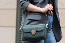 A Woman Holds A Green Handbag In The City. Close-up Image. The Concept Of Luxury