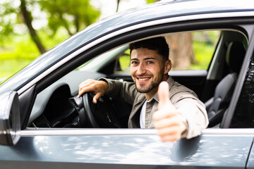 Young man smiling happy doing ok sign driving car.