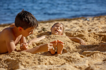 Sticker - Child, tickling sibling on the beach on the feet with feather, kid cover in sand, smiling, laughing