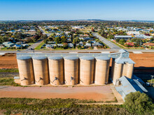 Sunlit Grain Silos With Backdrop Of Rural Town Houses Of Coolamon