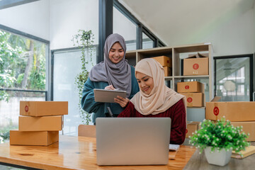 Friend muslim female work independent business sme online shopping working on laptop computer with parcel box on desk at home, SME online business and delivery concept