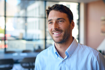 Portrait Of Smiling Businessman Standing In Empty Office 