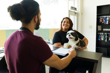 Cheerful pet groomer talking to a dog owner at the spa