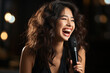 © Concept Island - Young Korean girl singing happily at karaoke, microphone in hand. Background with bokeh.