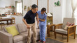 © PR Image Factory - korean woman in-home care attendant assisting senior male to stand up from the sofa at home. the senior patient using a crutch is feeling great pain in his knee joints