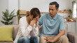 © PR Image Factory - asian Japanese grandfather trying to comfort and encourage sad adult granddaughter on sofa at home. he taps her back while she covers her face feeling frustration
