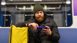 © makedonski2015 - A male courier watches movies on his phone while riding the subway for an order. Metro is the fastest form of public transport