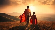 Dad And Son In Hero Superhero Costume Standing On Mountain At Sunset, Rear View.
