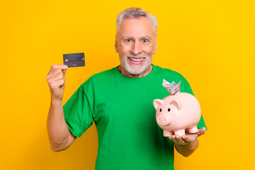 Sticker - Photo of good mood excited guy dressed green t-shirt holding bank card money box isolated yellow color background