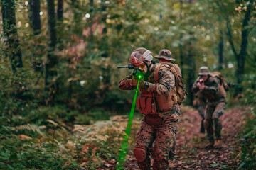 Wall Mural - A group of modern warfare soldiers is fighting a war in dangerous remote forest areas. A group of soldiers is fighting on the enemy line with modern weapons. The concept of warfare and military