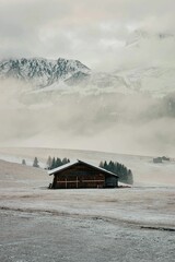 Canvas Print - Winter scene featuring a snow-covered landscape with a house in the middle of the frame.