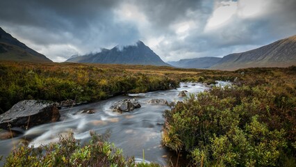 Poster - Picturesque mountain landscape showcasing a tranquil river flowing over rocks and stones