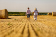 Grandmother walking on meadow with her grandson. Relaxing and joying in sunset.	