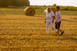 Grandmother walking on meadow with her grandson. Relaxing and joying in sunset.	