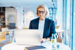 © okrasiuk - Portrait of concentrated 50's confident mature businesswoman, middle-aged experienced senior female professional working on laptop in open space office. Female entrepreneur working remotely
