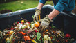 Leinwandbild Motiv Person composting food waste in backyard compost bin garden